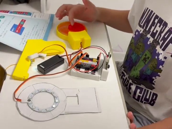扇風機とフルカラーLED、ボタンをつないだ作品で、ボタンを押してプログラムを試している手元