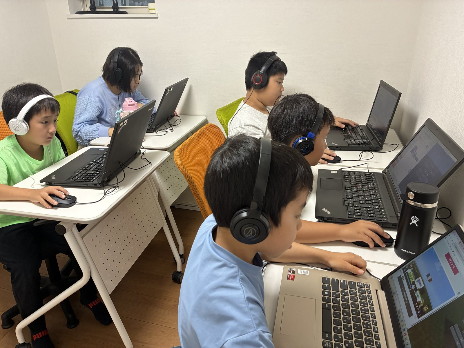 教室で、ヘッドホンをつけた子どもたちがそれぞれのノートパソコンに向かって作品をつくる様子