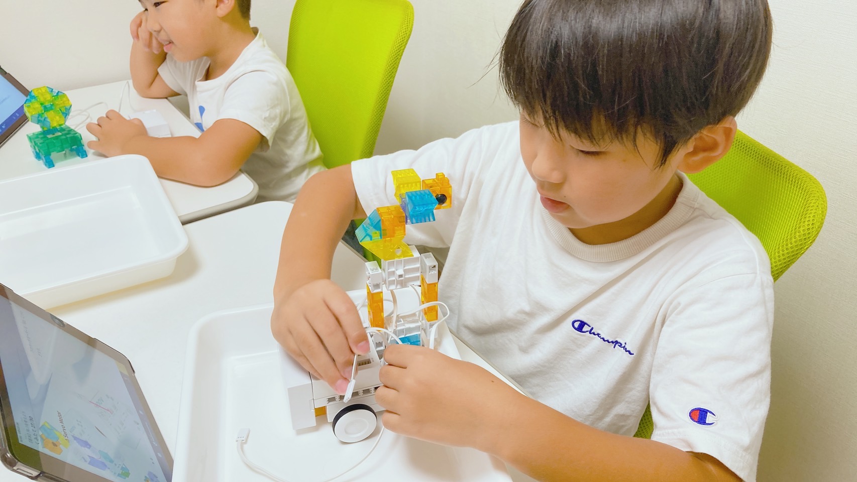 KOOVのロボットの配線を、集中して調整する子ども
