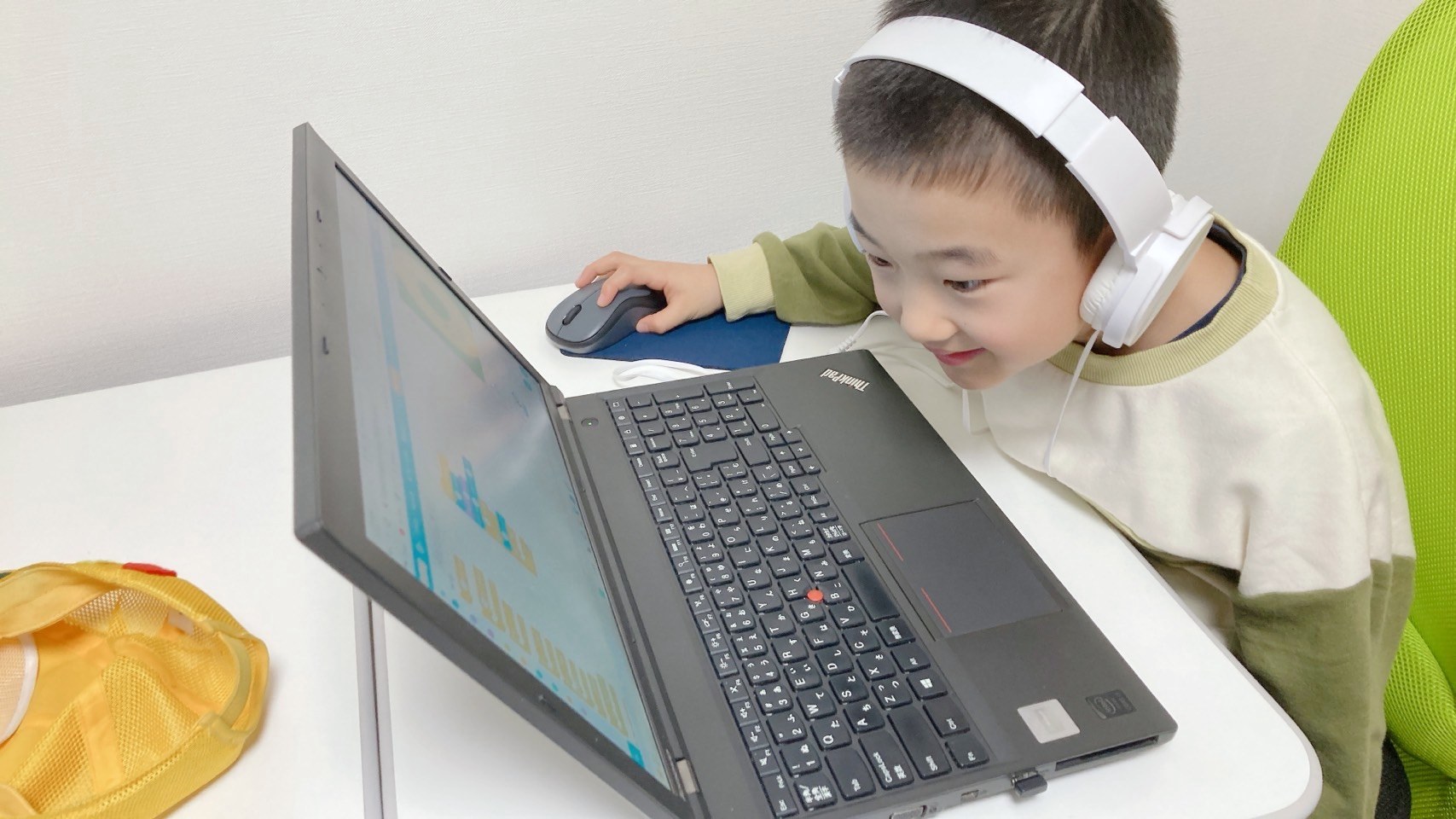 ヘッドホンをつけてノートパソコンに向かう子ども