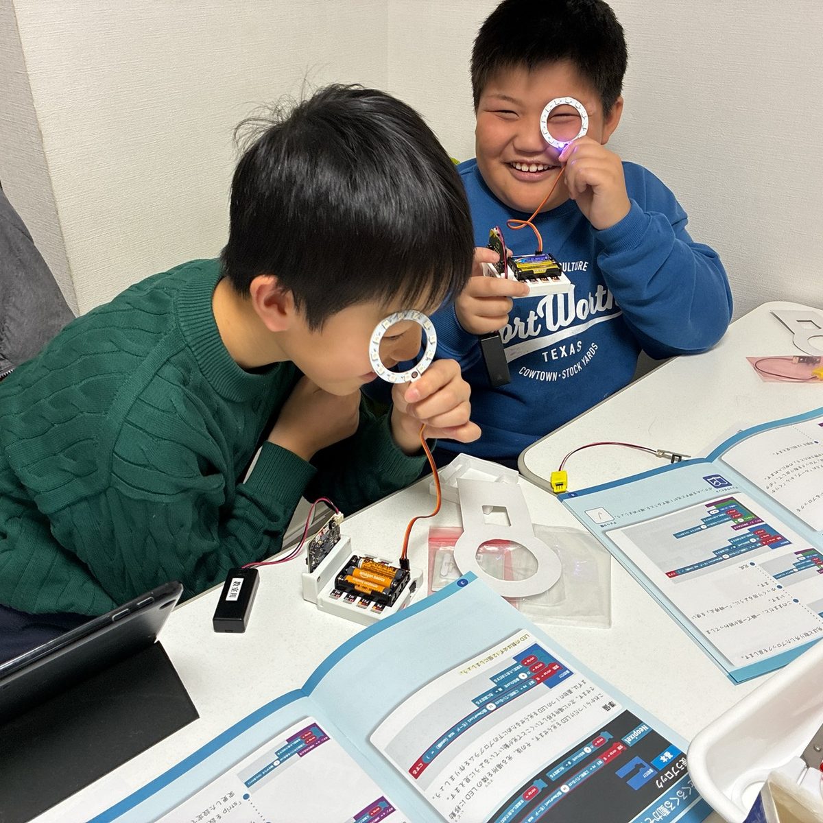 自分たちで作った光るLEDリングを目に当てて、笑い合う二人の子ども