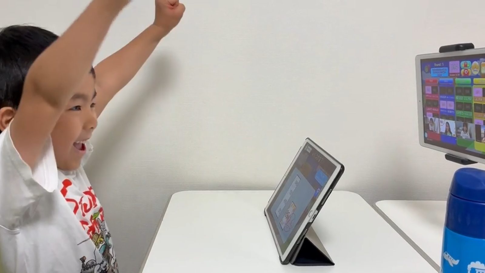 そろタッチのタブレットの前で、両手を上げて喜ぶ子ども